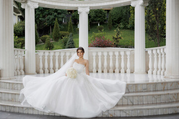 Elegant bride poses in beautiful white gown at outdoor venue during daylight
