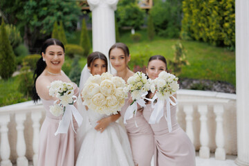 Joyful wedding celebration with bridesmaids in elegant attire holding floral arrangements