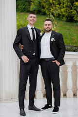 Two well-dressed men celebrating at a formal event in an elegant outdoor setting
