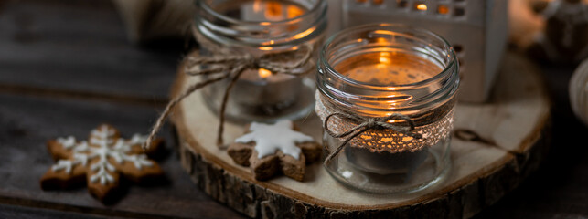 Creating holiday mood, festive atmosphere at home. Christmas spirit, atmospheric composition with handmade aroma candles made from simple glass jars, homemade gingerbread cookies, anise cinnamon scent