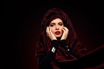 Beautiful young woman in luxurious style with red attire and striking makeup on a gradient...