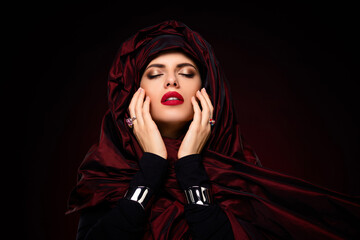 Tempting young woman with striking red makeup exuding charm and sophistication in elegant red toned...