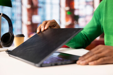 Teleworker at home office desk opening laptop lid to edit documents, updating reports and files....