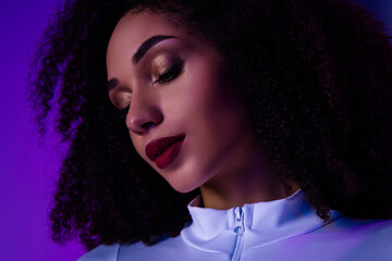 Expressive portrait of a glamorous young woman with bold makeup in neon violet light