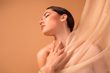 Beautiful portrait of a young brunette woman enveloped in sheer fabric, emphasizing natural beauty