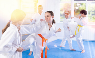 Group of preteen children in kimono practicing karate in a sports gym. Martial arts training session © JackF