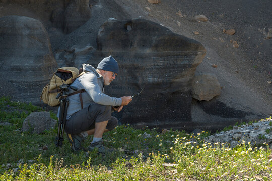 Senior Hiker preparing to take a video in a rocky and grass landscape