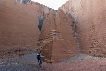 Hiker gazing at the Immense Walls of a Red Rock Quarry in Lanzarote