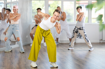 Group of sporty teenagers practicing hip-hop dance in training hall during dancing classes
