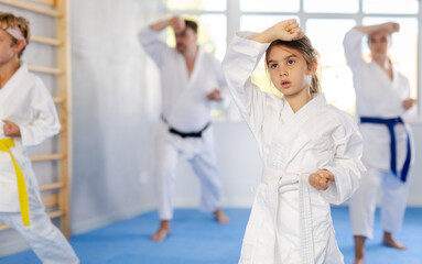 Family of karatekas with two children practicing karate techniques in gym