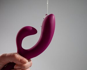 Lube pouring on pink dildo on white background. 