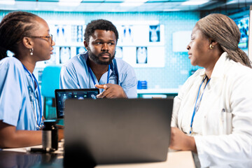 Team of trainee nurses analyzing patient health records during a meeting, utilizing x ray and mri...
