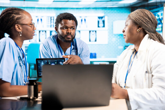 Team of trainee nurses analyzing patient health records during a meeting, utilizing x ray and mri scans with expert physician for a training session. Assistants work with medic.