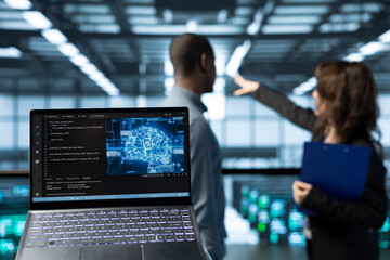Laptop in front of data center technicians in blurry background deploying AI driven management...