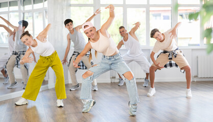 Active teenagers practicing hip-hop dance in training hall during group dancing classes