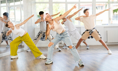 Stylishly dressed teenagers learn to dance hip-hop and breakdance in a dance studio