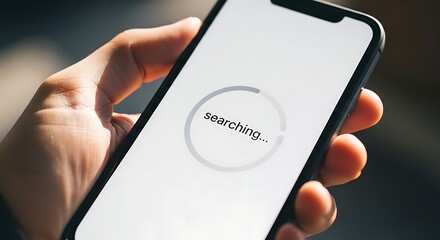 Hand holding a smartphone displaying a searching indicator on a bright white screen device close up