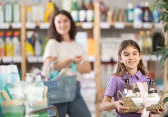 Girl holds a set of care shampoos, bath foam and shower gel in her hands, beautifully packed in a...