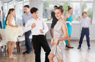 Teen girl in elegant evening dress dances incendiary twist with boy partner during choreography...