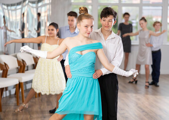 Boy and girl rehearsing social couples ballroom dance in studio