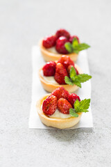 Wild strawberry tartlet. Light gray background. Close up
