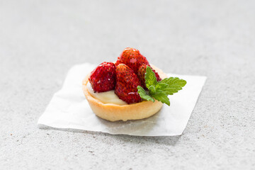 Mini tartlet. With Wild strawberries, custard and mint. Light background. Close up