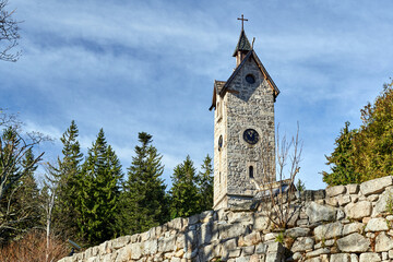 Stone wall and bell tower of the Wang Temple with a clock in Karpacz