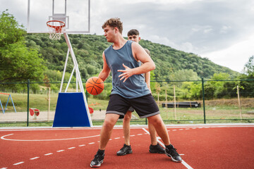 teenagers playing one on one basketball on an outdoor court