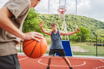 teenagers playing one on one basketball on an outdoor court