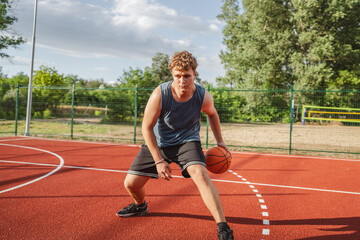 young man player dribbling ball on basketball court