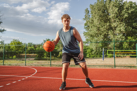 young man player dribbling ball on basketball court