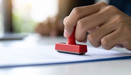 Hand stamping an official document with a red stamp, close up shot 