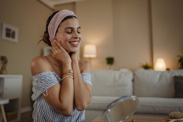 Smiling relaxed dark haired woman making anti-aging face massage