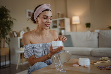 relaxed woman putting cream on her face to take care of her skin