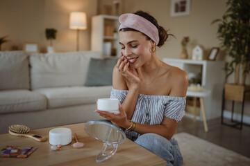 relaxed woman putting cream on her face to take care of her skin