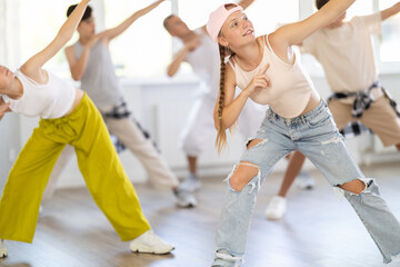 Stylishly dressed teenagers learn to dance hip-hop and breakdance in a dance studio