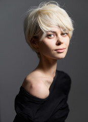 Stylish young woman with short white hair posing in a modern outfit, exuding confidence and charm...