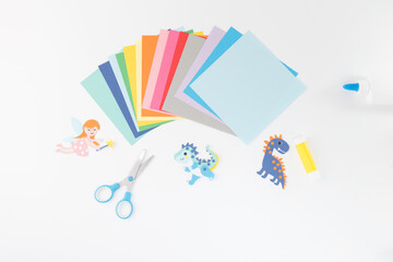 Top-down layout of kids DIY supplies with dinosaur and fairy cutouts, ideal for educational...