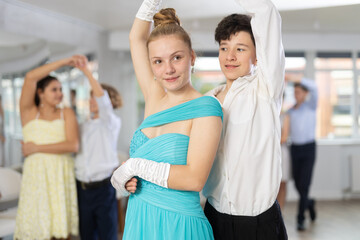 With unhurried music, teen boy and girl in couple spins to rhythm of tango during lesson for novice...
