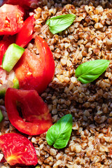 Healthy food without meat with buckwheat and a salad of chopped tomatoes, cucumbers, onions and basil leaves. The photo is suitable for the topic of healthy lifestyle and healthy eating