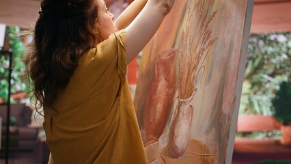 In a rustic atelier, painter mixes watercolor paint on a palette to create a masterpiece on canvas....