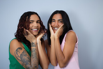 Two sisters smiling at camera, with hands on chin. Ideal for friendship, gossip, happiness,...