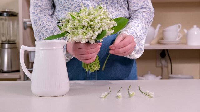Florist creates a beautiful bouquet of lilies of the valley and places it in a vase as Easter decoration. Calm spring scene in 4K.