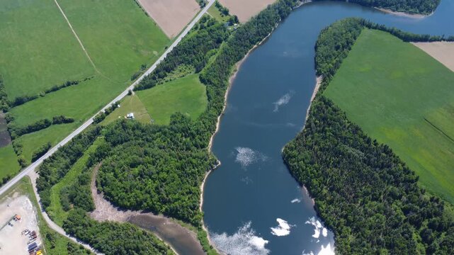 High-altitude drone footage shows the famous Mitis River and Mitis-2 hydroelectric dam surrounded by forests and agricultural fields in Price, Quebec, Canada.