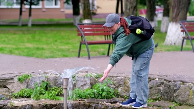 Spontaneous Joy: Woman Dip Her Hands Into Fountain Lines And Relaxes In City Park.