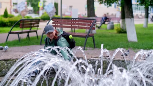 Spontaneous Joy: Woman Dip Her Hands Into Fountain Lines And Relaxes In City Park. Video 4K