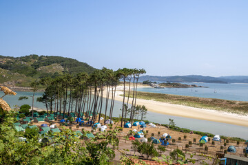 Camping site at Cíes Islands in Vigo, Galicia, Spain, surrounded by turquoise sea and pine...