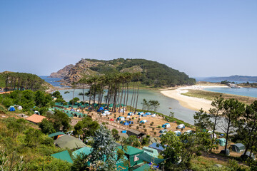 Camping site at Cíes Islands in Vigo, Galicia, Spain, surrounded by turquoise sea and pine...