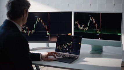 Crypto trader analyzing stock charts on laptop at office over shoulder view - Powered by Adobe