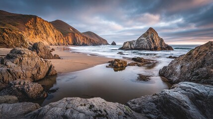 Obraz premium Beach scene with rock formations and cliffs under a cloudy, golden-hour sky